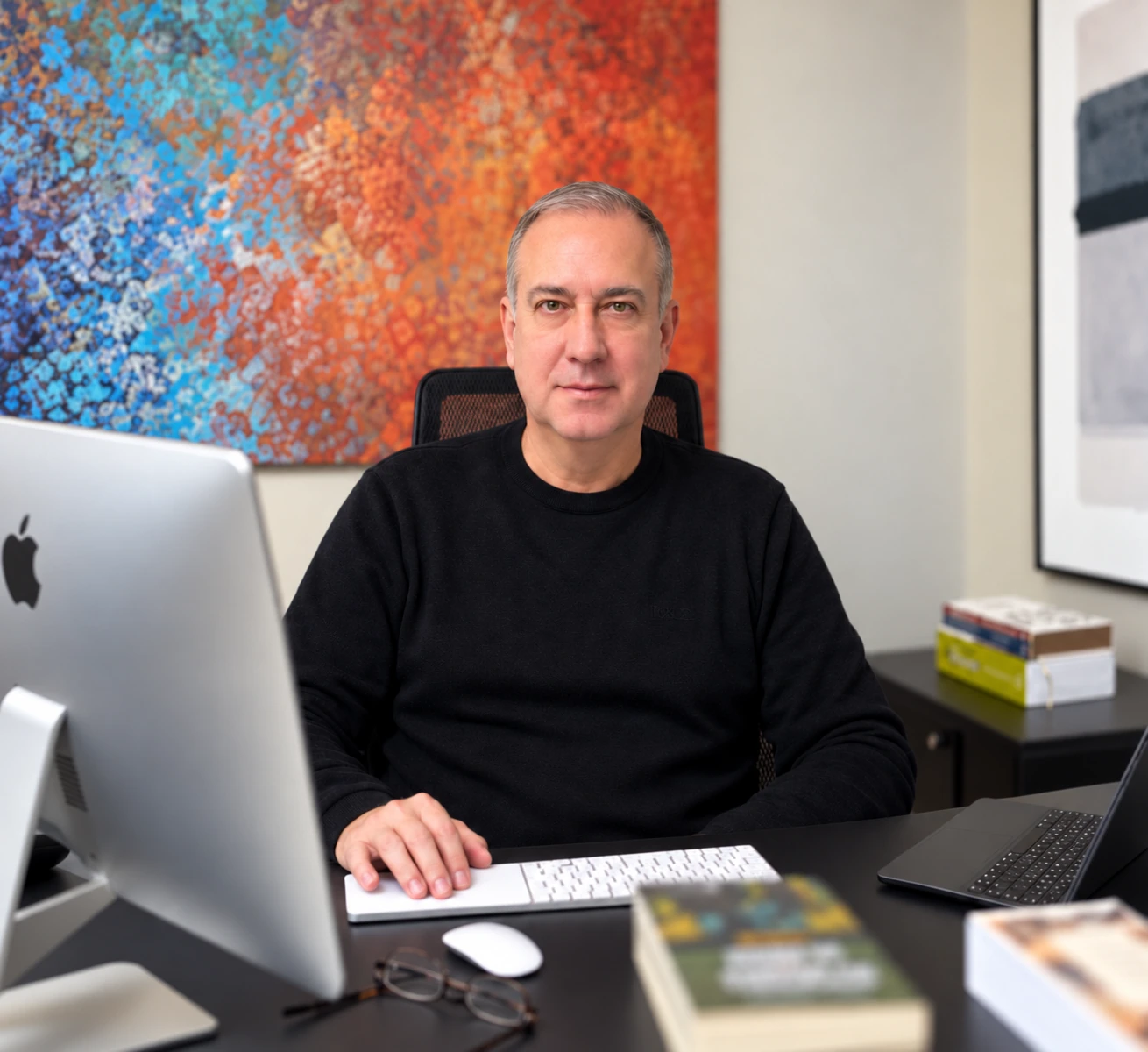 Marcelo Cardoso em seu escritório, à mesa com computadores e livros
